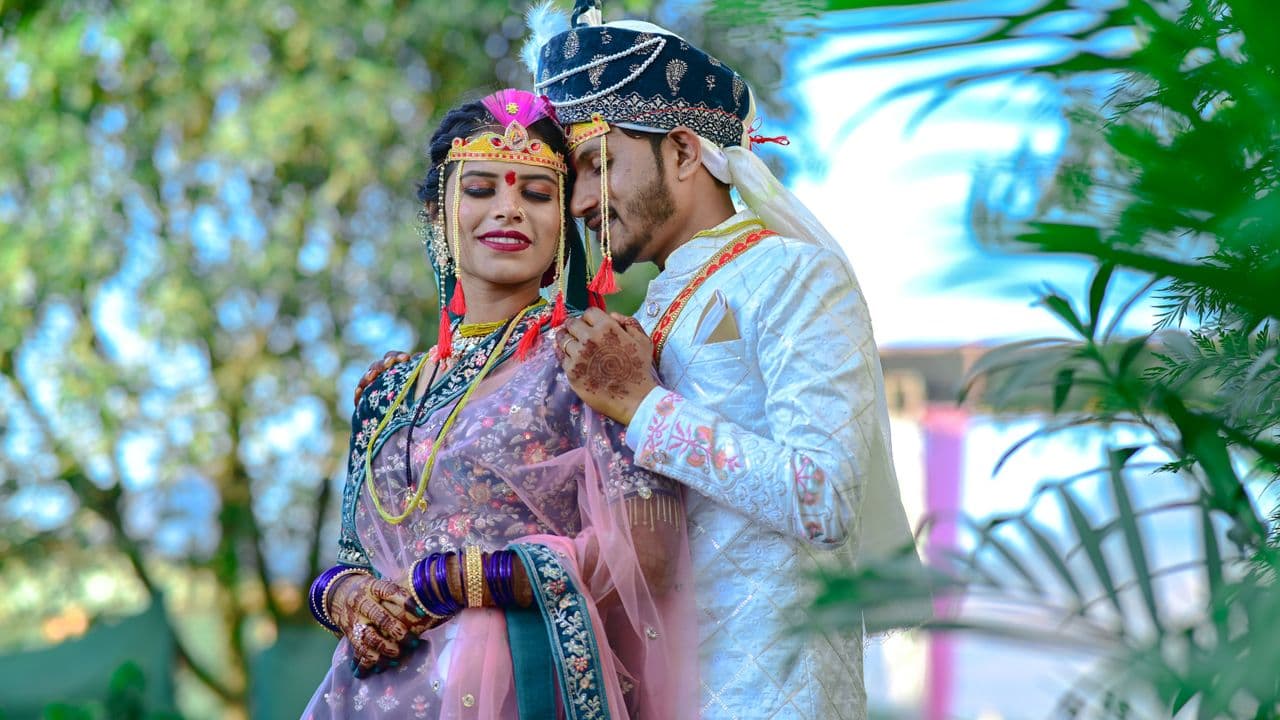 A couple in traditional Indian wedding attire celebrating outdoors
