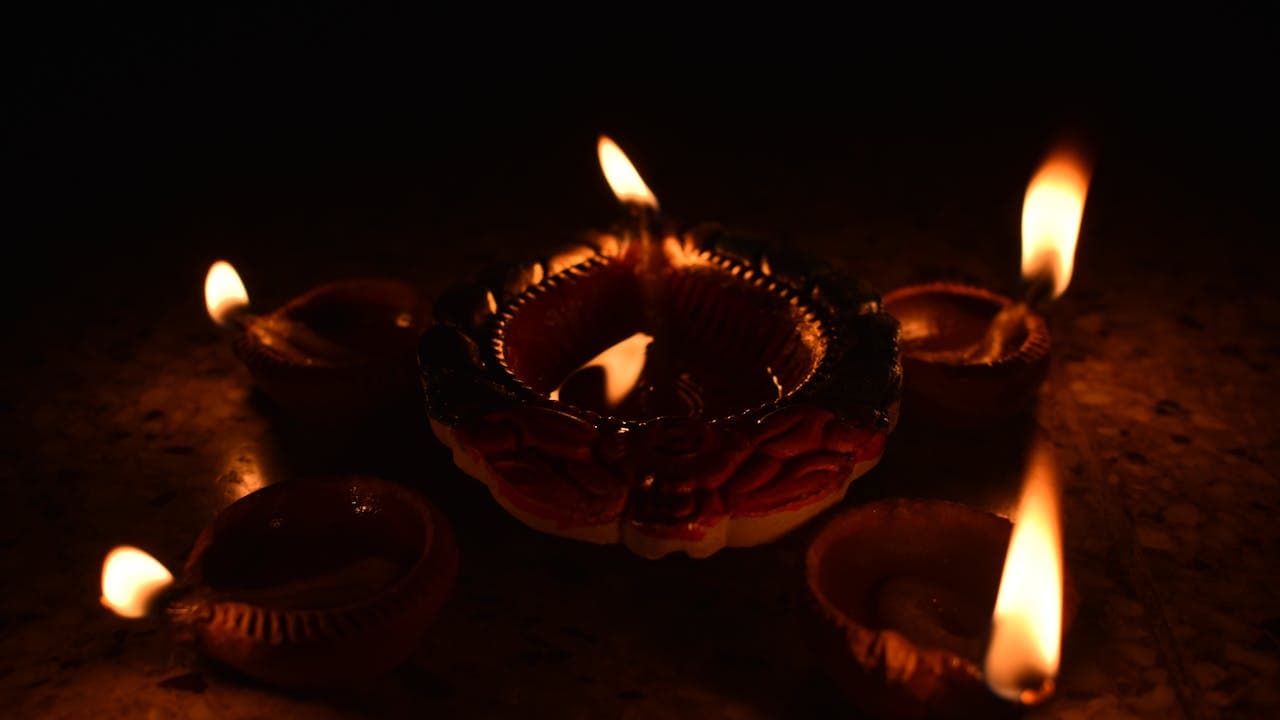 Rows of lit Diwali diyas glowing in the dark